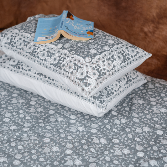 Floral-patterned pillowcases on a bed with a visible brand tag.